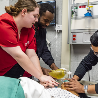 Three nursing students performing CPR on a medical manikin